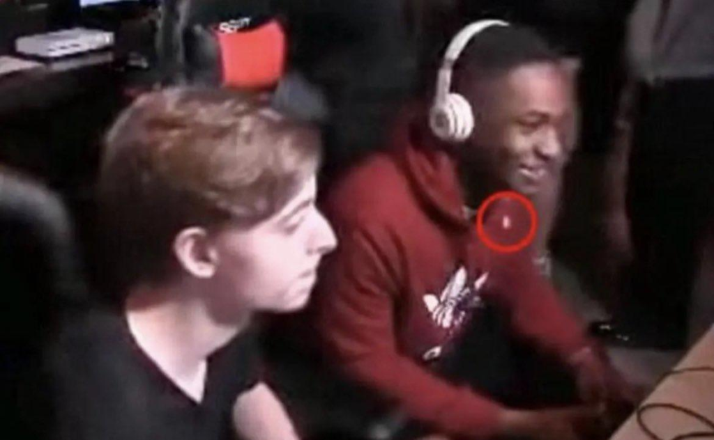A still from the tournament's Twitch livestream showing Elijah Clayton seconds before the shooting, with the red laser sight from David Katz's gun visible on his chest.