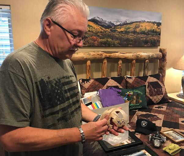 Allyn Atadero holds the skull fragment recovered from the Big South Trail in 2003, kept alongside Jaryd's belongings including his Oakland Raiders cap.