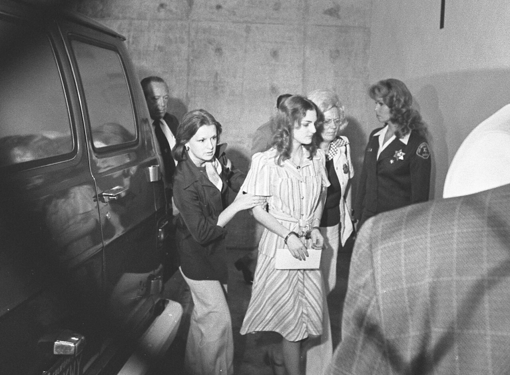 Patty Hearst Went From Kidnapping Victim to Wanted Bank Robber 5 Patty Hearst, handcuffed, is led by marshals to a courthouse hearing in 1976 during her trial for bank robbery.